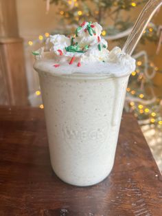 a cup filled with whipped cream and sprinkles on top of a wooden table