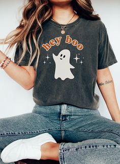 a woman sitting on the ground with her legs crossed and wearing a t - shirt that says hey boo