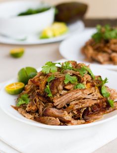 an easy crockpot carnitas recipe on a white plate with cilantro