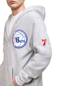 a young man wearing a grey sweatshirt with the philadelphia 76ers on it's chest