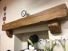 a wooden shelf with flowers and a clock on the wall