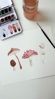 an artist's paintbrush, watercolor paints and mushrooms on a white surface