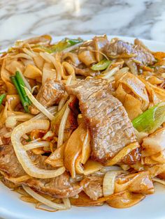 a white plate topped with meat and noodles