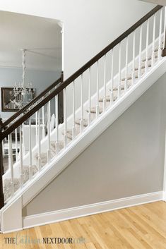 a white stair case in a house with wood floors and hard wood flooring on the stairs