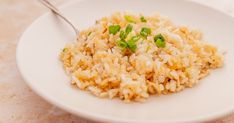 a white plate topped with rice and green onions