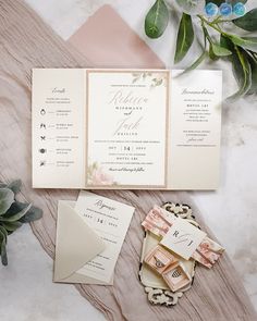 the wedding stationery is laid out on a table with flowers and greenery around it