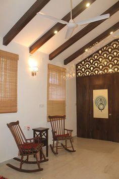 two rocking chairs are in the middle of a room with wood slats on the ceiling