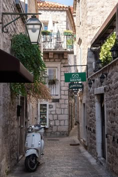 a scooter parked on the side of a narrow alleyway in an old town