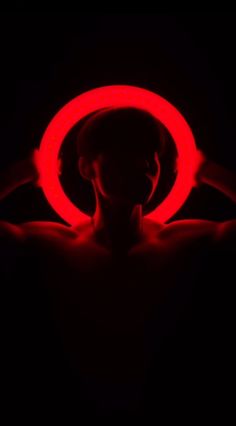 a person holding a red ring in the dark with their arms spread out to show it's shape