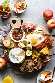 an assortment of food on a platter with fruit, bread and juices around it