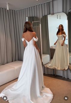 a woman in a white dress looking at herself in the mirror