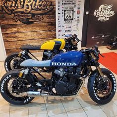 a blue and yellow motorcycle on display in a showroom next to a wooden sign