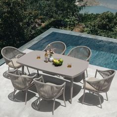 an outdoor dining table with six chairs next to a swimming pool