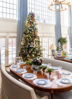 a dining room with a christmas tree in the center and blue drapes on the windows