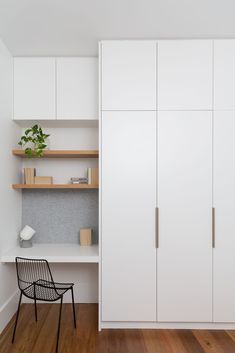 a white closet with shelves and a chair in the corner, next to a wooden floor