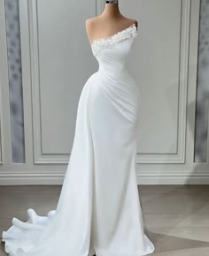 a white wedding dress with an off the shoulder neckline