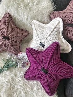 three knitted star pillows sitting on top of a white rug