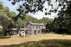 a large gray house sitting in the middle of a forest