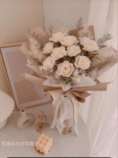 a bouquet of white flowers sitting on top of a table next to a framed photo