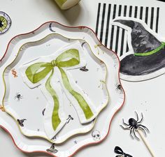 a paper plate with a green bow on it next to halloween decorations and spider stickers