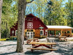 a red barn with picnic tables in front of it and trees around the building area