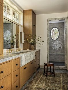 a bathroom with wooden cabinets and marble counter tops, along with a large round window