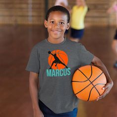 a young boy is holding a basketball and smiling at the camera while other children are running in the background