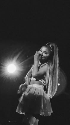 a black and white photo of a woman on stage with her hands in her mouth