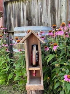 a wooden bird house sitting in the middle of flowers