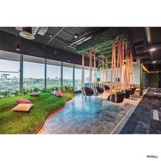 the interior of an office building with grass on the floor and hanging chairs in front of large windows