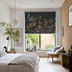 a bedroom with a bed, chair and window covered in blinds that have tropical plants on them