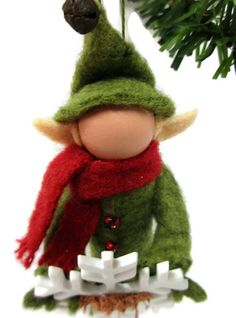 an ornament hanging from a tree with a red scarf and green hat on it