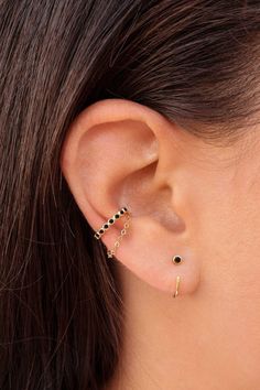 a woman's ear with two small black stones on it