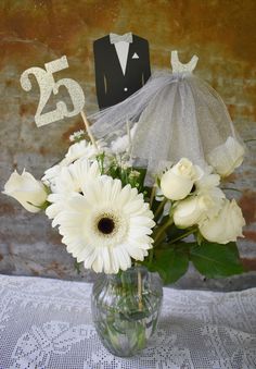 a vase filled with white flowers on top of a table next to a sign that says 25th anniversary