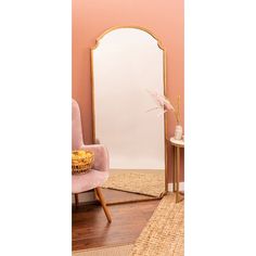 a mirror sitting on top of a wooden floor next to a pink chair and table