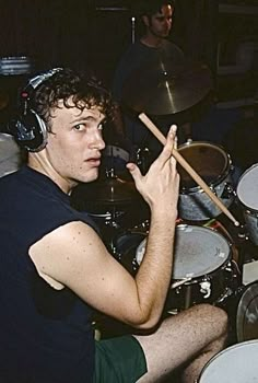 a young man sitting in front of a drum set with headphones on his ears