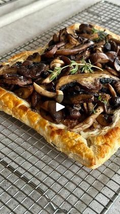 a square pastry topped with mushrooms on top of a cooling rack