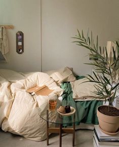 a room with a bed, plant and books on the table in front of it