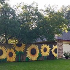 a sunflower painted on the side of a fence in front of a brick house