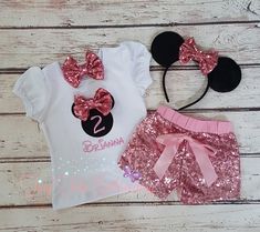 two minnie mouse outfits with pink sequin shorts and headbands on a white wooden background