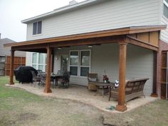 a covered patio with chairs and table in the back yard