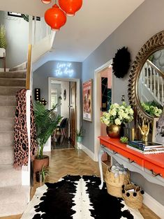 the hallway is decorated with black and white cowhide rugs, red table runner, and gold accents