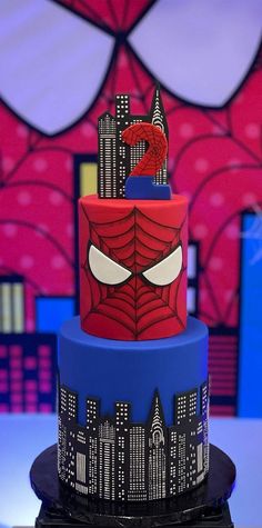 a spiderman themed cake on top of a table with cityscape in the background