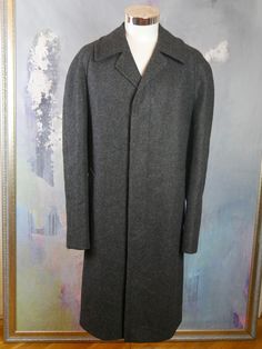 This charcoal gray wool overcoat has a notch collar, and closes in the front with three concealed buttons. The 1990s classic European vintage winter coat has raglan-style sleeves, two slanted hip pockets, and a center vent in the back that ensures complete ease of movement. The overcoat is lined in a dark blue satin viscose fabric, and has one inner pocket. Brand label: Ora (Finland ... but made with Scottish wool from Henry Ballantyne of Scotland) Size: 46 US/UK Material: Wool ---MEASUREMENTS-- Classic Gray Wool Coat For Winter, Classic Gray Wool Coat For Fall, Classic Gray Wool Coat With Pockets, Classic Gray Wool Coat With Lapel Collar, Classic Gray Wool Coat For Business, Gray Classic Wool Coat For Formal Occasions, Classic Gray Outerwear With Hidden Button Closure, Classic Gray Wool Coat, Classic Gray Outerwear With Lapel Collar