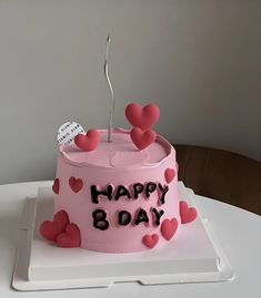 a pink birthday cake with hearts on it