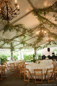 the inside of a tent with tables, chairs and chandelier hanging from the ceiling