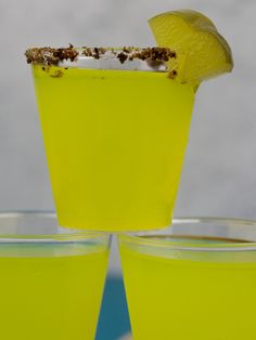 three glasses filled with yellow liquid and topped with a slice of lemon