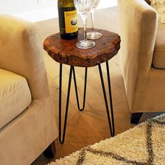 a table with a wine glass on it next to two chairs and a couch in the background