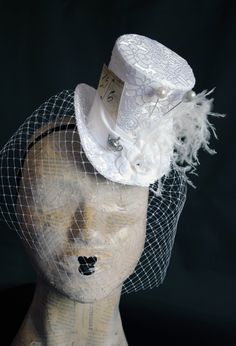 A Mad Hatter mini top hat with a bridal twist! The hat is covered with beautiful textured white brocade and embellished with white taffeta ribbon around the crown. Trimmed with pearl hats pins, white roses,white feather spray, the signature 10/6 Mad Hatter card and of course a tiny silver tea-pot! Cause around here it's always tea-time! Both hat pins have push-in clasps to avoid accidents! IMPORTANT NOTE: The fabric used in the original design is permanently OUT OF STOCK. Please check out the NE Vintage Costume Hats And Headpieces For Wedding Carnival, Vintage Top Hat With Curved Brim For Costume Party, Vintage Curved Brim Top Hat For Costume Party, Victorian Adjustable Top Hat With High Crown, Elegant Costume Hats And Headpieces With Pinched Crown, Elegant Costume Hat With Pinched Crown, Elegant Costume Hats With Pinched Crown, Adjustable Brimmed Victorian Top Hat, Whimsical Wedding Headpieces For Carnival