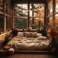 a bed sitting under a window in a bedroom next to a table with two vases on it